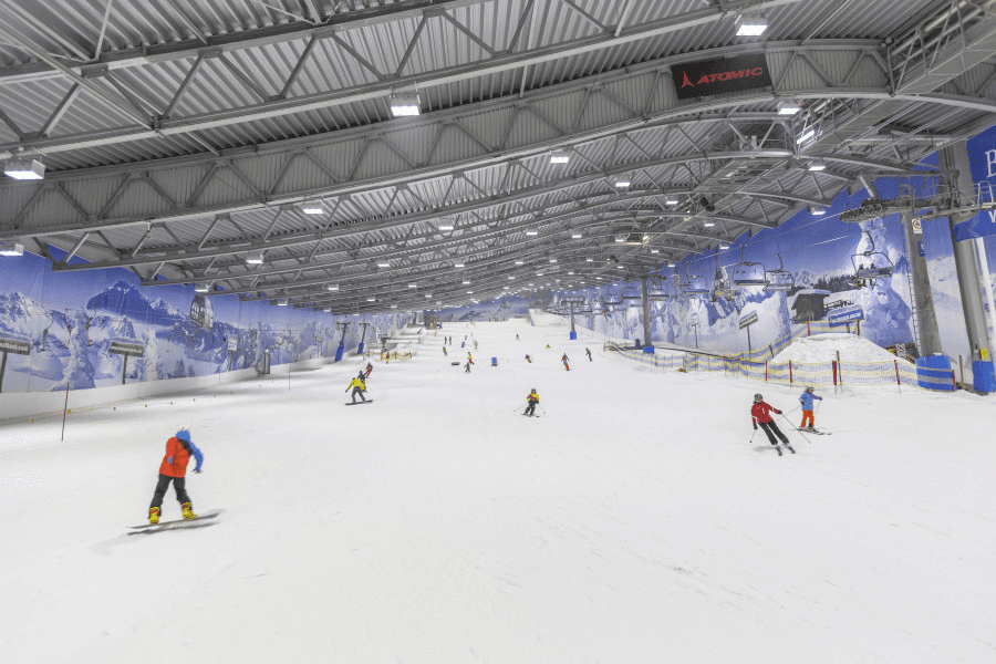 Indoor ski center slope with guests preparing for a timed session